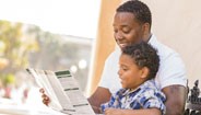 father and son looking at booklet