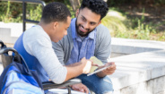 two men sitting outside looking at tablet